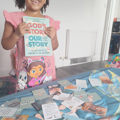 Child holding God’s Story, Our Story book with companion Bible cards spread out